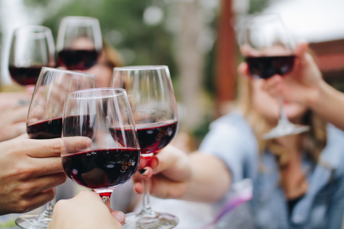 Hands raising a toast with glasses of red wine